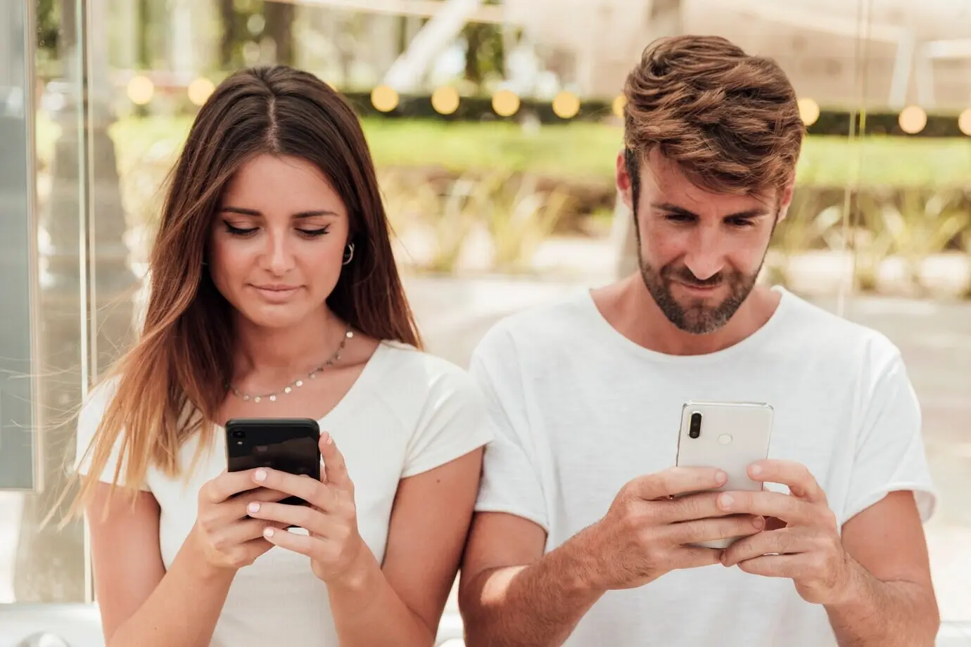 Мужчина и женщина переписываются на смартфонах.